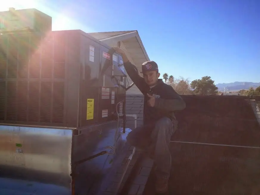 HVAC technician performing Air Duct Repair on a rooftop unit in Fort Bragg